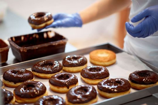 pastelero bañando donuts en chocolate